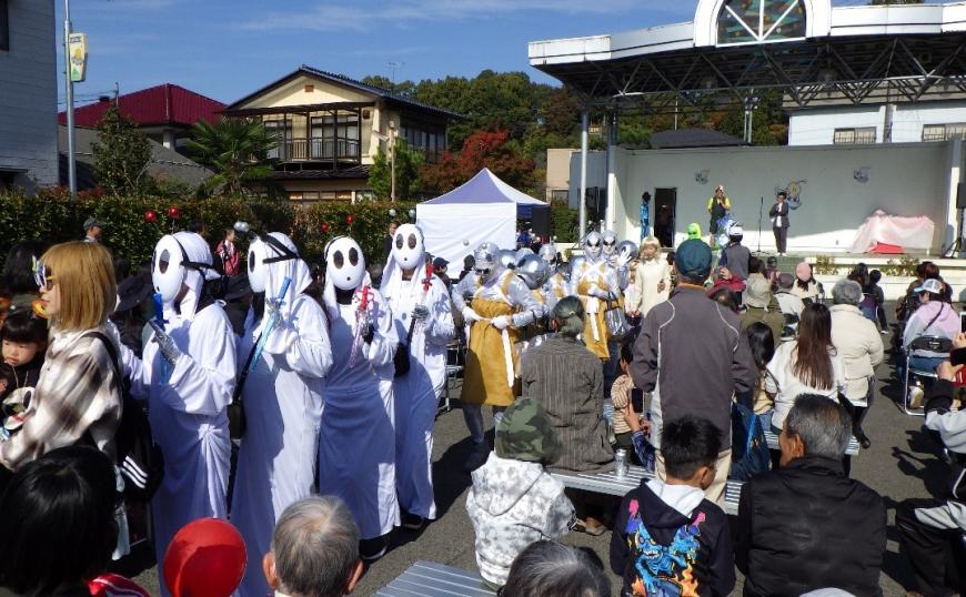 宇宙人のお面に白い衣装をした参加者が歩いている写真