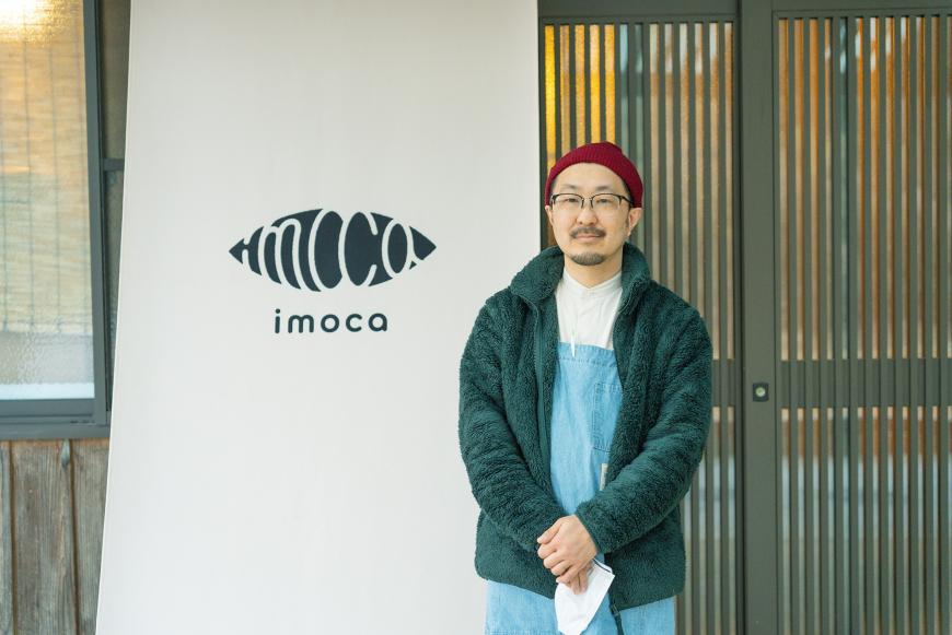 「imoca」と書かれた暖簾の前で大澤さんを撮影した写真