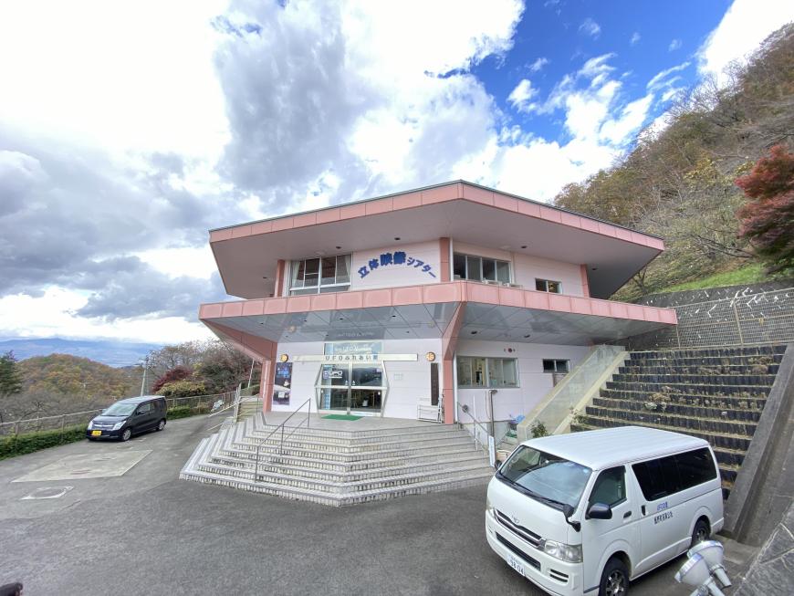屋根がピンク色で六角形の形をしたUFOふれあい館の外観写真