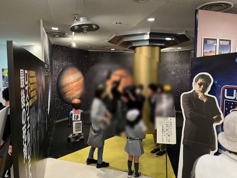 UFOのイベントのパネルの前で写真を撮る様子の参加者がモザイクのかかった写真