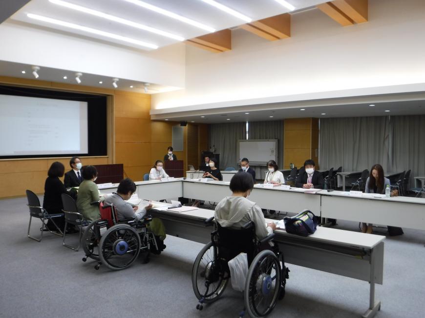 Uの字型に設置した長机の席に参加者が座り話し合いが行われている会議の様子の写真