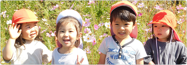 4人の子どもがコスモス畑を背景にそれぞれカメラに向かてポーズをとっている写真