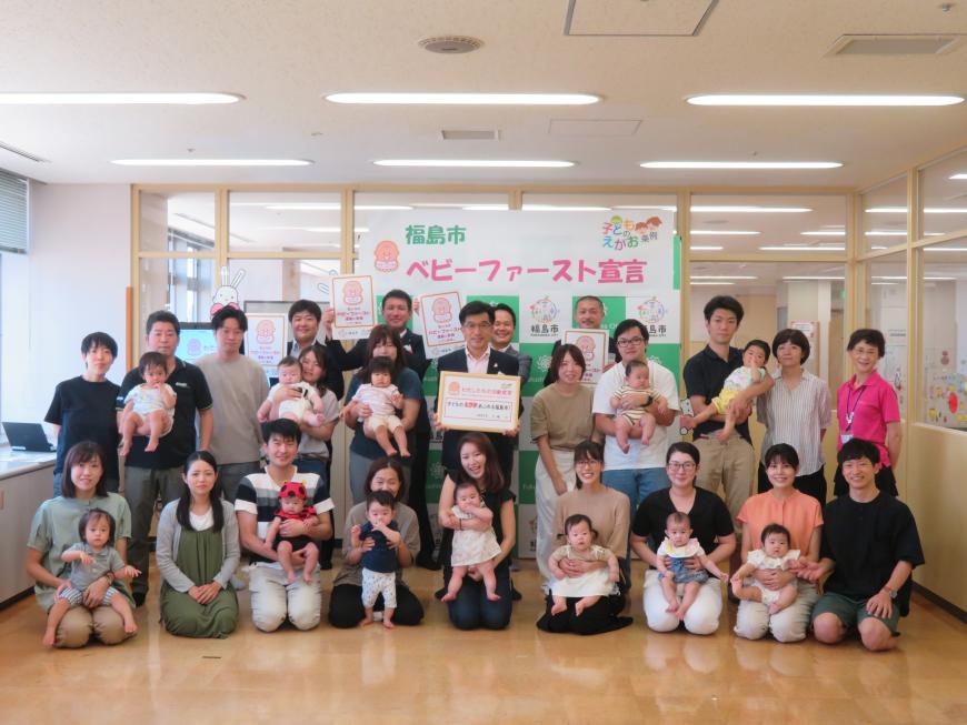 「福島市ベビーファースト宣言」と書かれた横断幕の前で市長を中心に小さい赤ちゃんを連れた親子連れ数組が集まっている集合写真