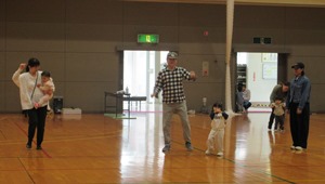 保護者と子どもが一緒に手を振りながらダンスをしている様子の写真