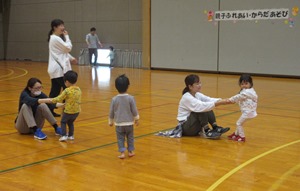 保護者の両手を掴んで後ろに引っ張ろうとしている様子の子どもの写真