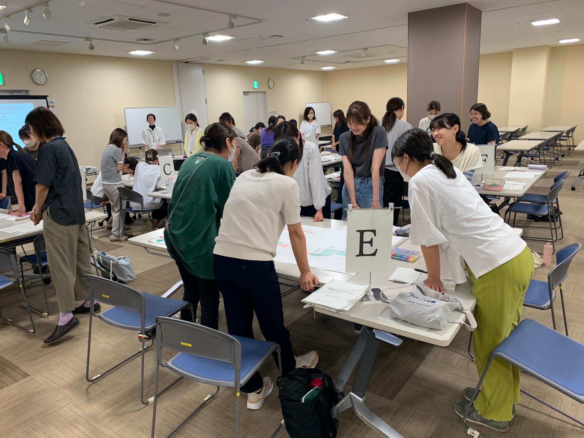 模造紙を広げたテーブルを囲んで座った参加者たちがペンを持って模造紙に書き込んでいる様子の写真