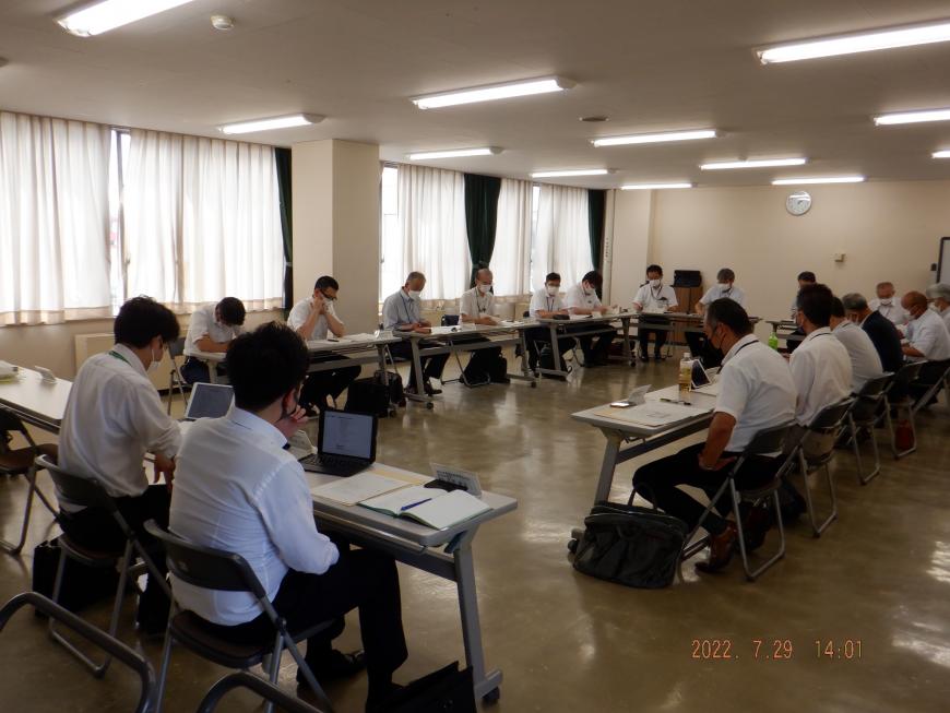 ロの字型に配置された長机にパソコンが置かれ、関係者たちが着席して会議を行っている総会の様子の写真