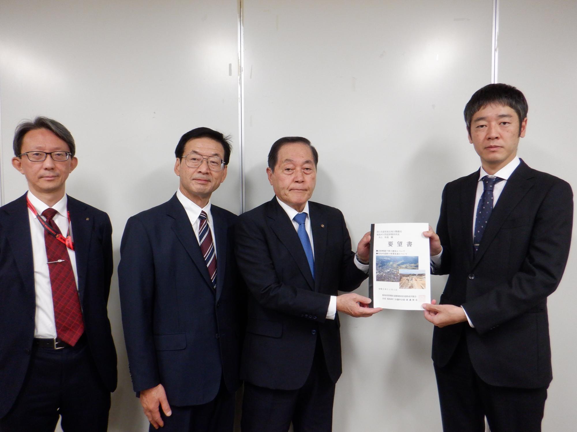 丸山和基事務所長と上森康幹副局長が要望書を持ち4人で横一列に並び記念撮影をしている写真