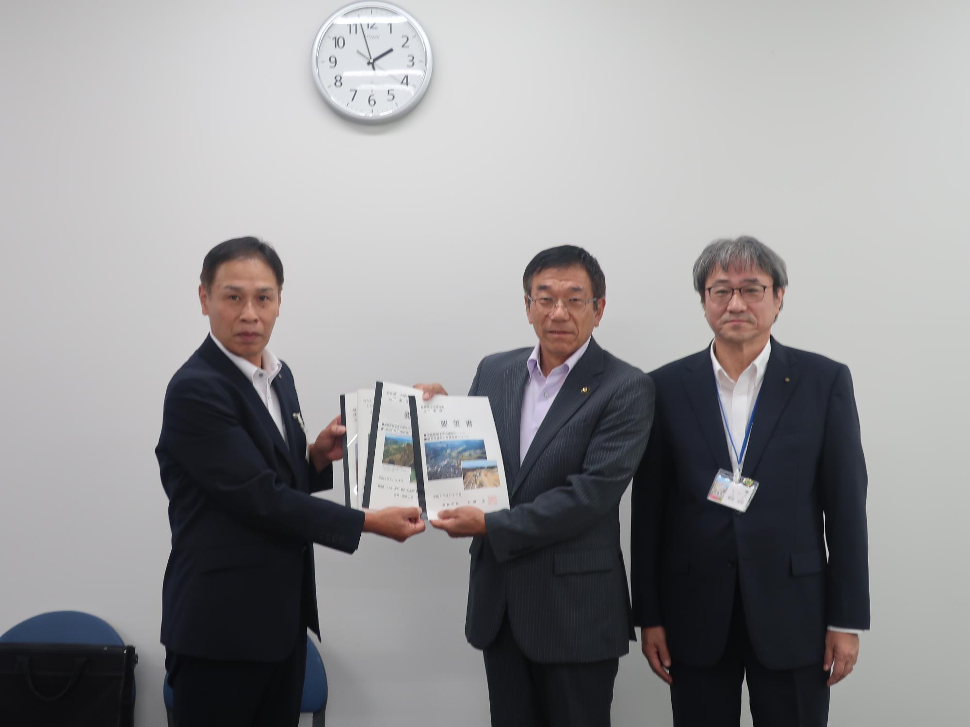 左側に山田毅技監と2人の関係者が横一列に並び要望書を持ち記念撮影をしている写真