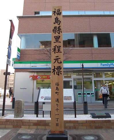 縦長の木材で造られ「福島縣里程元標」と黒文字で縦書きに書かれた木柱の写真