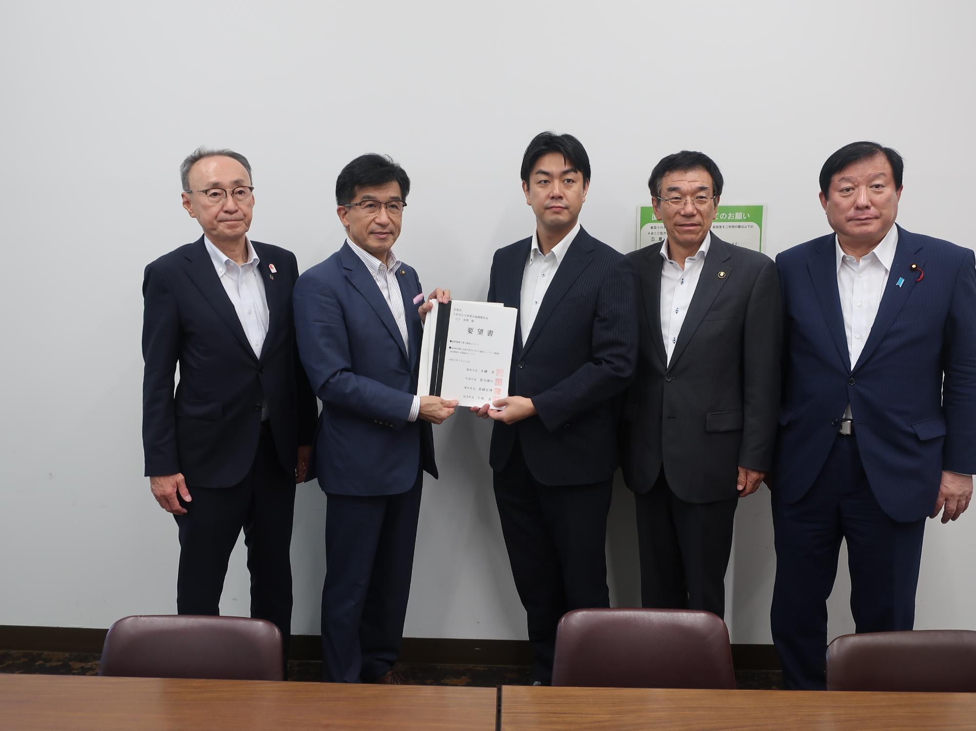 山下直樹公共事業企画調整室長を中心に5人の方が横一列に並び要望書を持ち記念撮影をしている写真