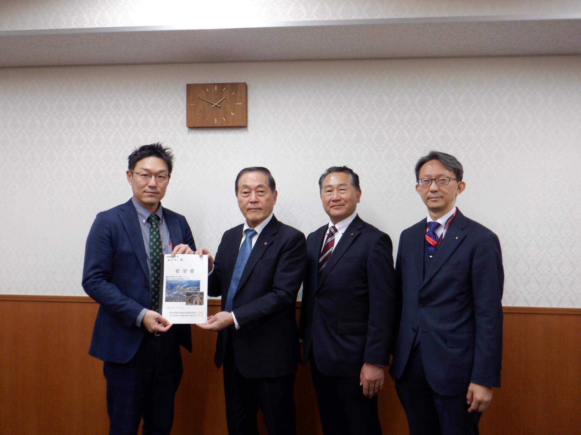 永田浩二主査と渡邊博美福島商工会議所会頭が要望書を持ち4人の方が横一列になり記念撮影をしている写真