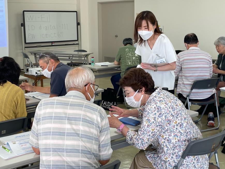隣り合わせに座った男性と女性が一生懸命に話をしている様子を、女性スタッフが笑顔で見つめている写真