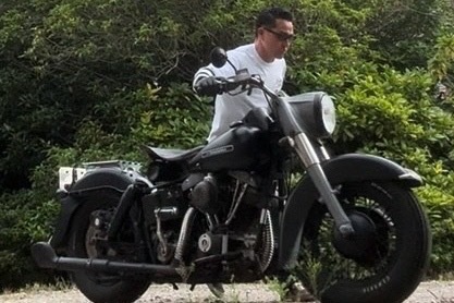 佐藤正徳さんが真っ黒で大きなバイクのハンドルを握って動かしている写真