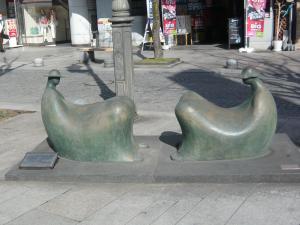 向かい合って座っている2人が椅子のようになっている作品「すわるふたり」の写真