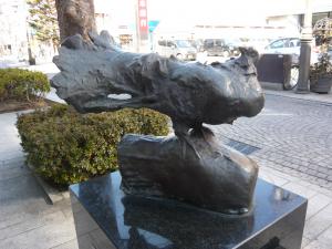 四角形の大理石の台の上に展示された大きなハトの彫刻作品「道標・鳩」の写真