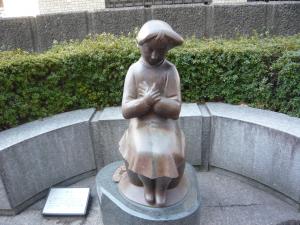 女の子が両手を重ねて胸に置いて座っている作品「思い出」の写真