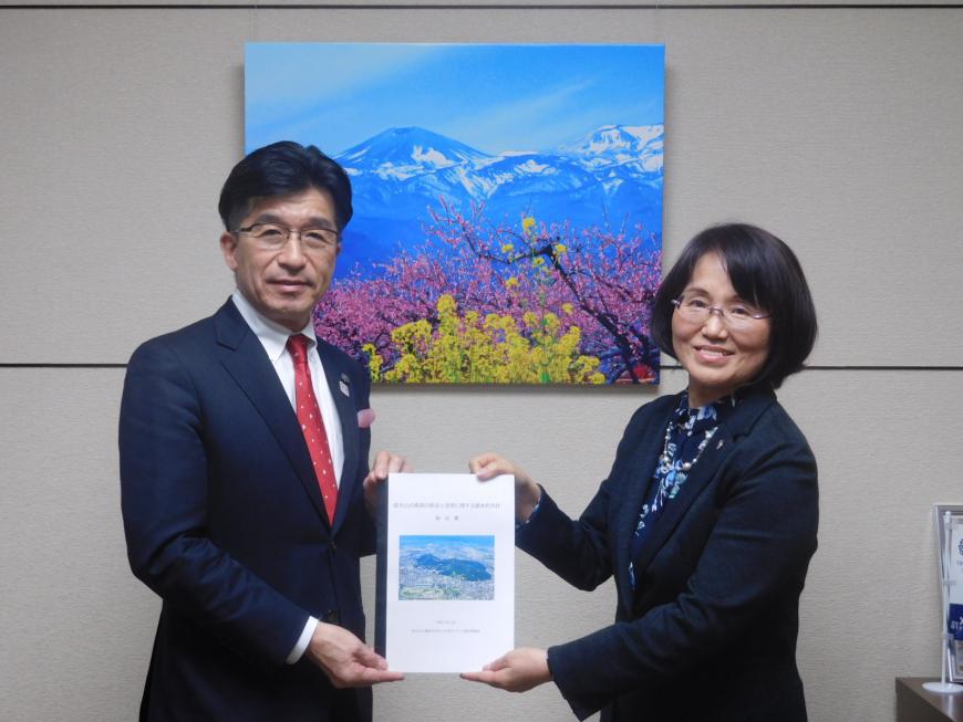 市長と女性が報告書を一緒に持ちながら記念撮影をしている写真