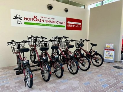 ももりんシェアサイクルの看板が壁に貼られた場所に自転車が数台停まっている写真