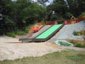 通常の滑り台より幅がある大型の滑り台が設置された土合舘公園内の遊具の写真