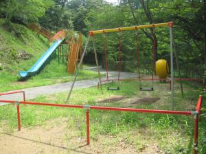 遊歩道に面してブランコと滑り台が設置されている弁天山公園内の遊具の写真