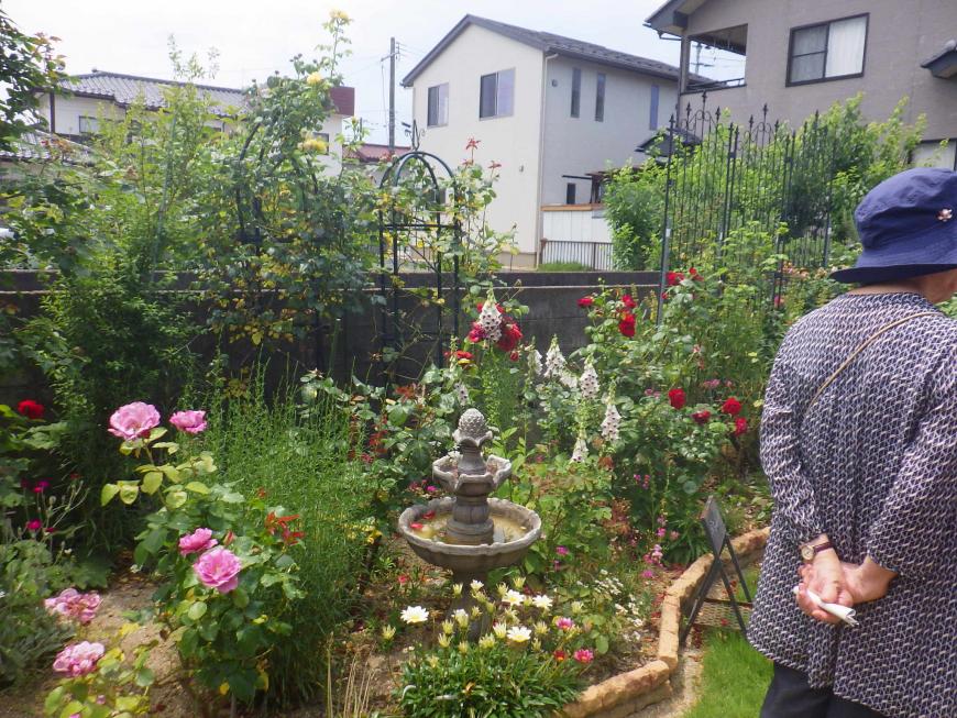小さな噴水のような置物などが花壇に置かれ周りを色とりどりな花が咲きほこっている庭の写真