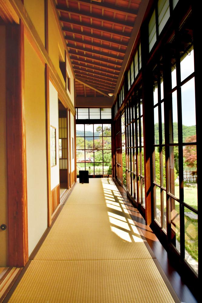 ガラス張りの窓から日差しが差し込んでいる御倉邸廊下の写真