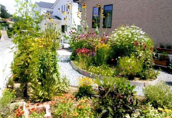 小道の両脇に設置された花壇に色とりどりの花が植えられている庭の写真