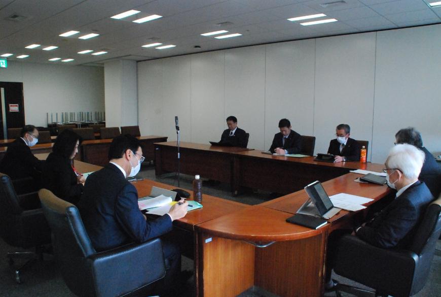 ロの字型の会議テーブルの席に関係者らが座っており、総務常任委員会が行われている写真