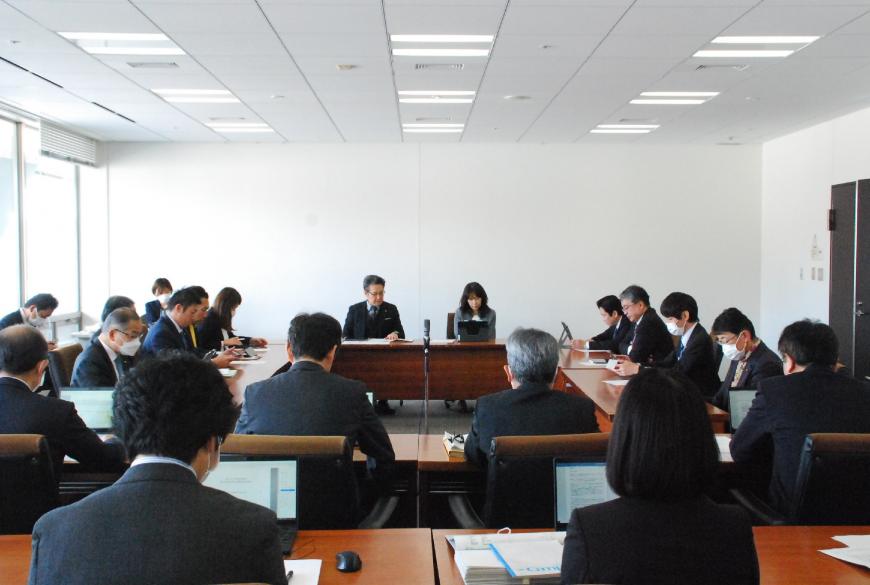 会議室に20人程の関係者が席に座り話しをしている写真