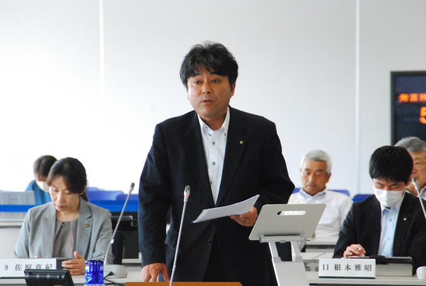 片手に資料を持ち登壇している石原洋三郎議員の写真