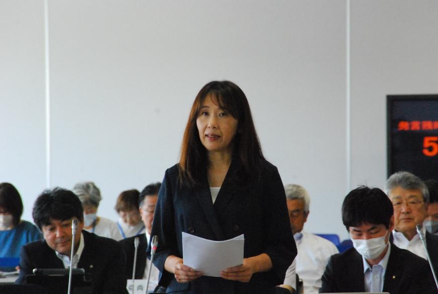 紺色のジャケットを着た佐原真紀議員が登壇している写真