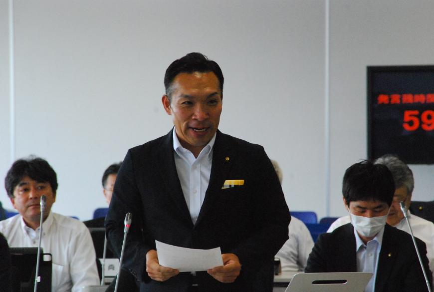 両手で資料を持ち登壇している佐藤勢議員の写真