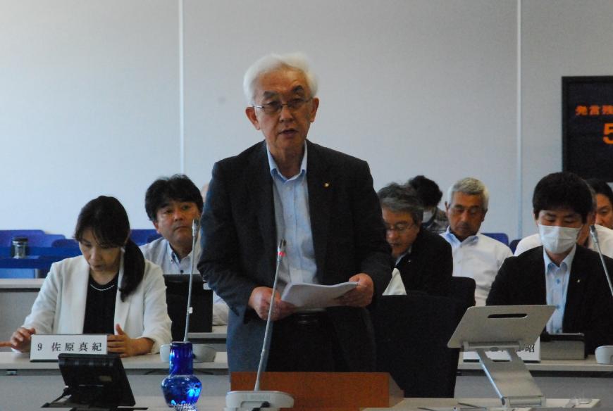 両手で資料を持ち登壇している山田裕議員の写真