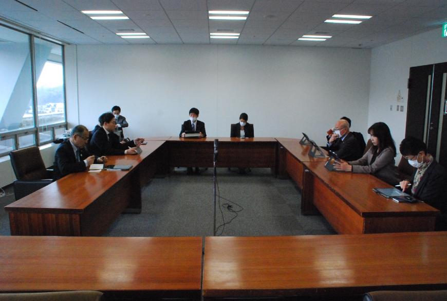 会議室でコの字型に配置されたテーブルに座り8名の方が協議をしている写真