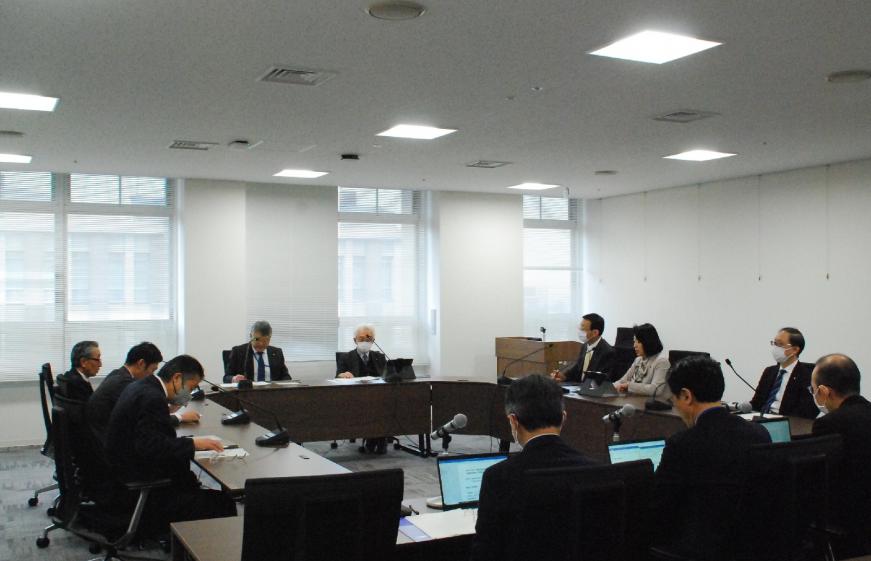 ロの字型に設置された机に委員の方々が座り、総務常任委員会が行われている様子を左後方から撮影した写真