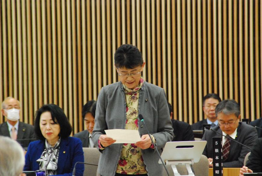 花柄のシャツにグレー色のジャケットを着た村山国子議員が、両手で持った資料を見ながら話をしている写真
