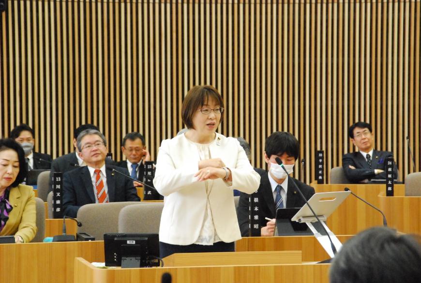 胸の高さまで上げた両手を重ねて手話をしながら話をしている三浦由美子議員の写真
