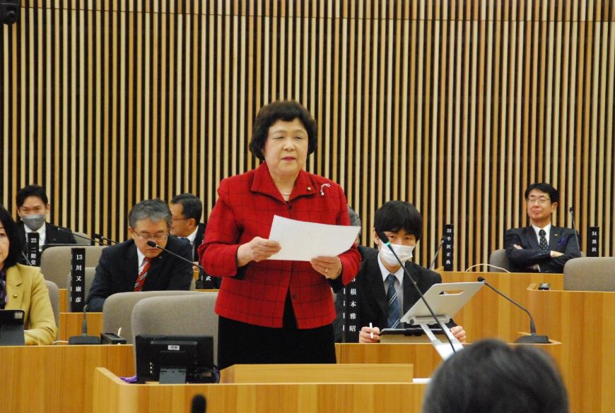 資料を両手で持ち真っ赤なジャケットを着た小野京子議員の写真