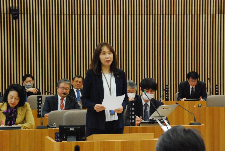 資料を両手で持ち真っすぐ前を向いて話をしている佐原真紀議員の写真