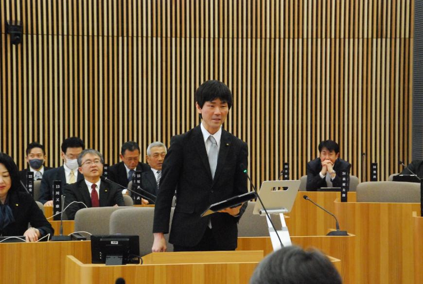 左手にタブレットを持ち話をしている根本雅昭議員の写真