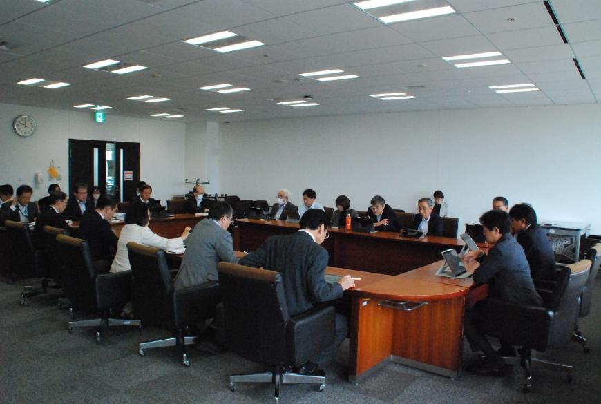会議室でロの字型に配置された机に委員が座り、各自タブレットの画面を見ながら協議をしている写真