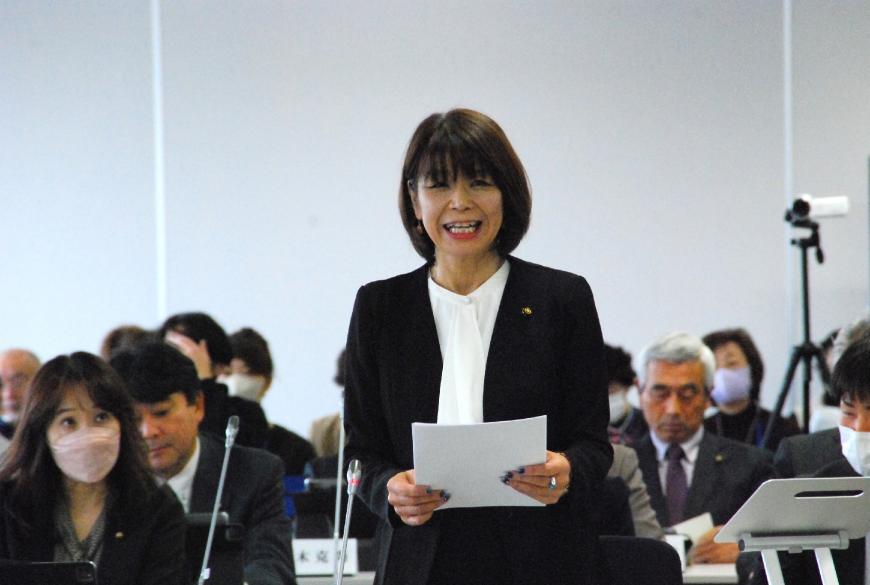 白いシャツに黒のジャケットを着た石山波恵議員が資料を両手で持ち真っすぐ前を向いて話をしている写真