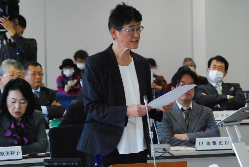 白いシャツに紺色のジャケットを着た村山国子議員が、資料を両手で持ち話をしている写真