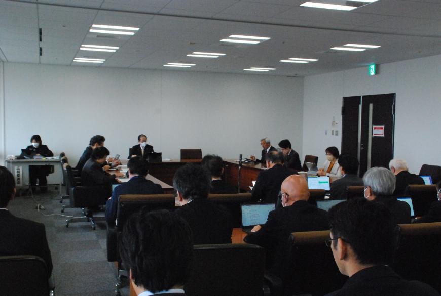 机がUの字型、奥に横並びに設置された席に委員の方々が座り、建設水道常任委員会が行われている様子を左後方から撮影した写真