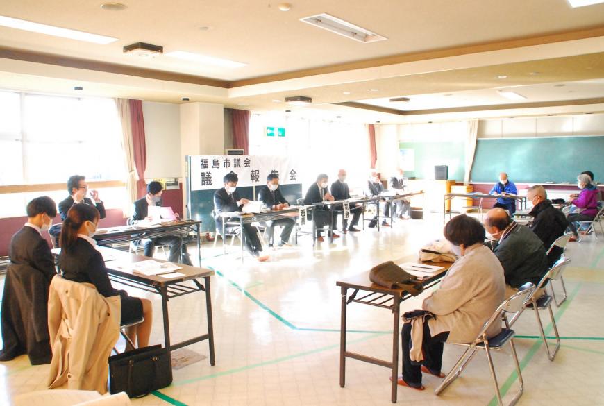 ロの字型に設置されたテーブルの前に関係者が座っている会議の様子の写真
