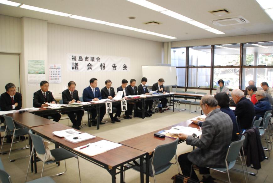 参加者と司会者が向き合って座り、手元の資料を見ながら意見交換会が開かれている様子の写真