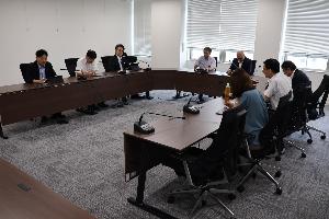 委員8名がコの字型のテーブルに座り、タブレット端末を見ながら協議している写真