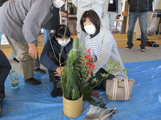 飾り付けられた門松を眺めている3人の女性の写真
