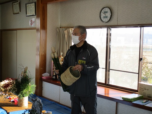 左手に3本の竹、右手に縄を巻いた缶を持っている男性の写真